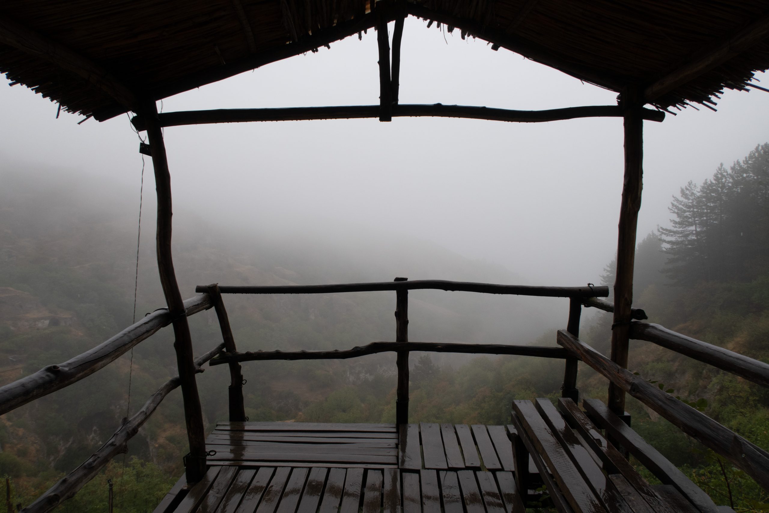 Fog view on the wooden eco trail in Khndzoresk ancient cave city in the mountain rocks. Armenia landscape attraction. Abandoned ruins in the mist. Atmospheric stock photography.